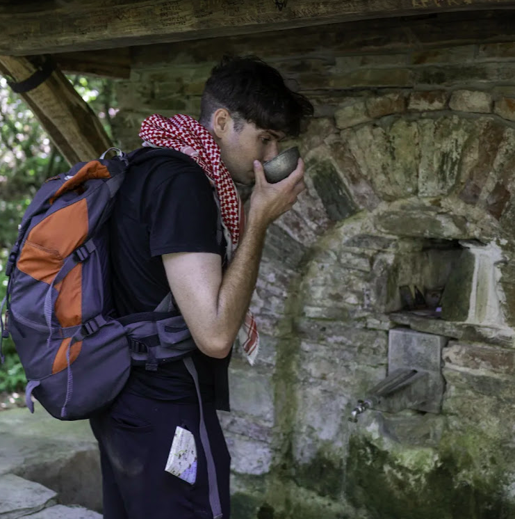 Cameron drinking from a well